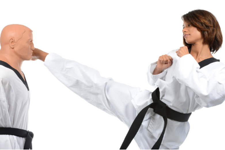 womens-self-defense woman in martial arts outfit with a black belt kicking a dummy to the head with a right round kick