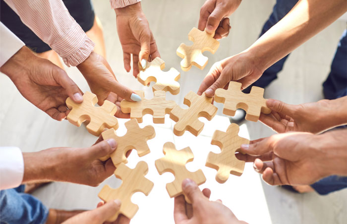 teambuilding-700px photo of hands all holding puzzle pieces together