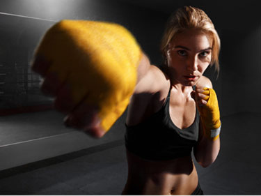 woman in a cardio kickboxing class wearing yellow gloves punching straight toward the camera