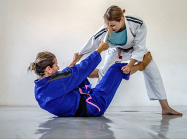 women in martial arts uniform doing jiu jitsu