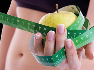 hand holding an apple with a measuring tape wrapped around it