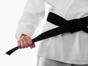 closeup photo of a person in a martial arts uniform holding the black belt on their uniform