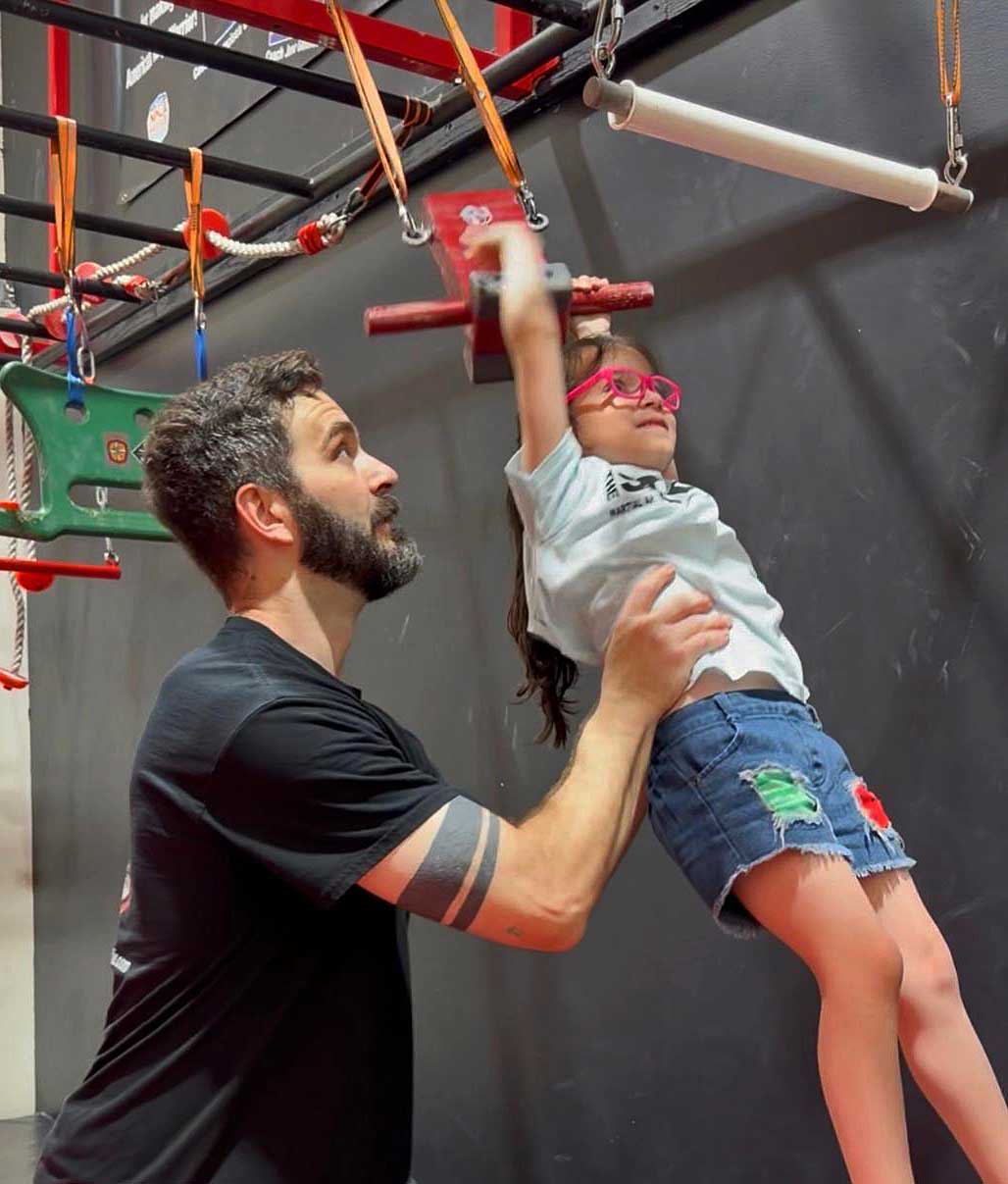 coach helping young girl on the ninja obstacle course