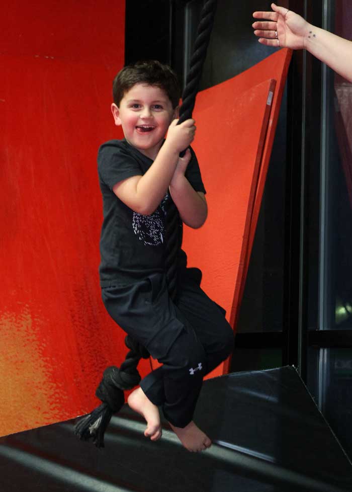 bday3 boy smiling while swinging on a rope on the ninja obstacle course at THE STUDIO martial arts, ninja gym and fitness in roseville