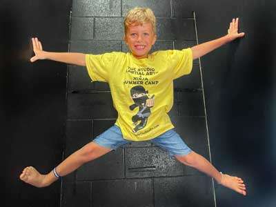 kid-ninja-wall boy in a yellow shirt having fun on the ninja warrior course at THE STUDIO Martial Arts, Ninja Gym and Fitness in Roseville