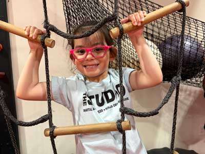 mini-ninja-girl little girl with glasses hanging on a cargo net