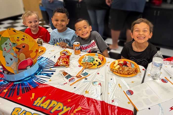 roseville-birthday-parties kids smiling at a table covered with birthday decorations during a kids birthday party in Roseville at THE STUDIO